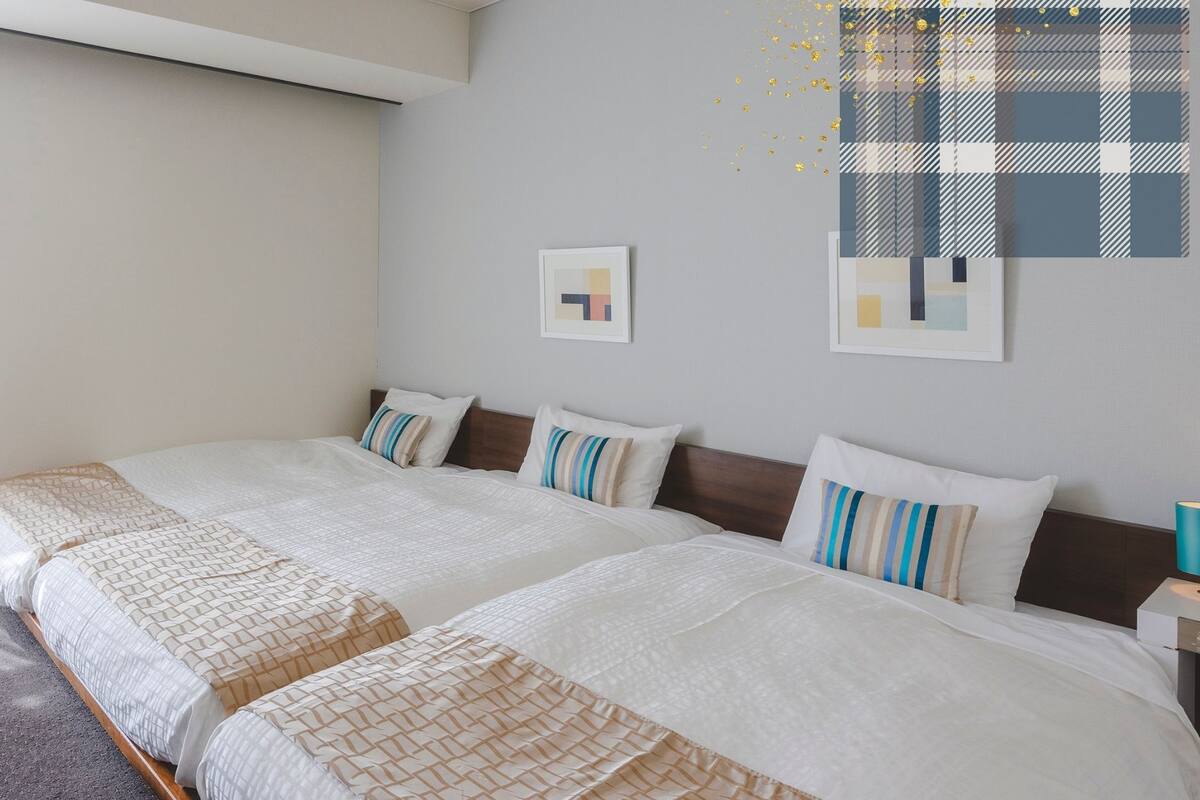 Habitación de hotel con dos camas, una mesita redonda y un sofá.