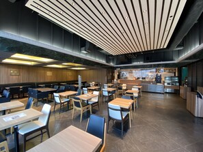 A modern restaurant with multiple tables and chairs, a bar area, and a kitchen in the background. - Hotel Gracery Sapporo (Sapporo)