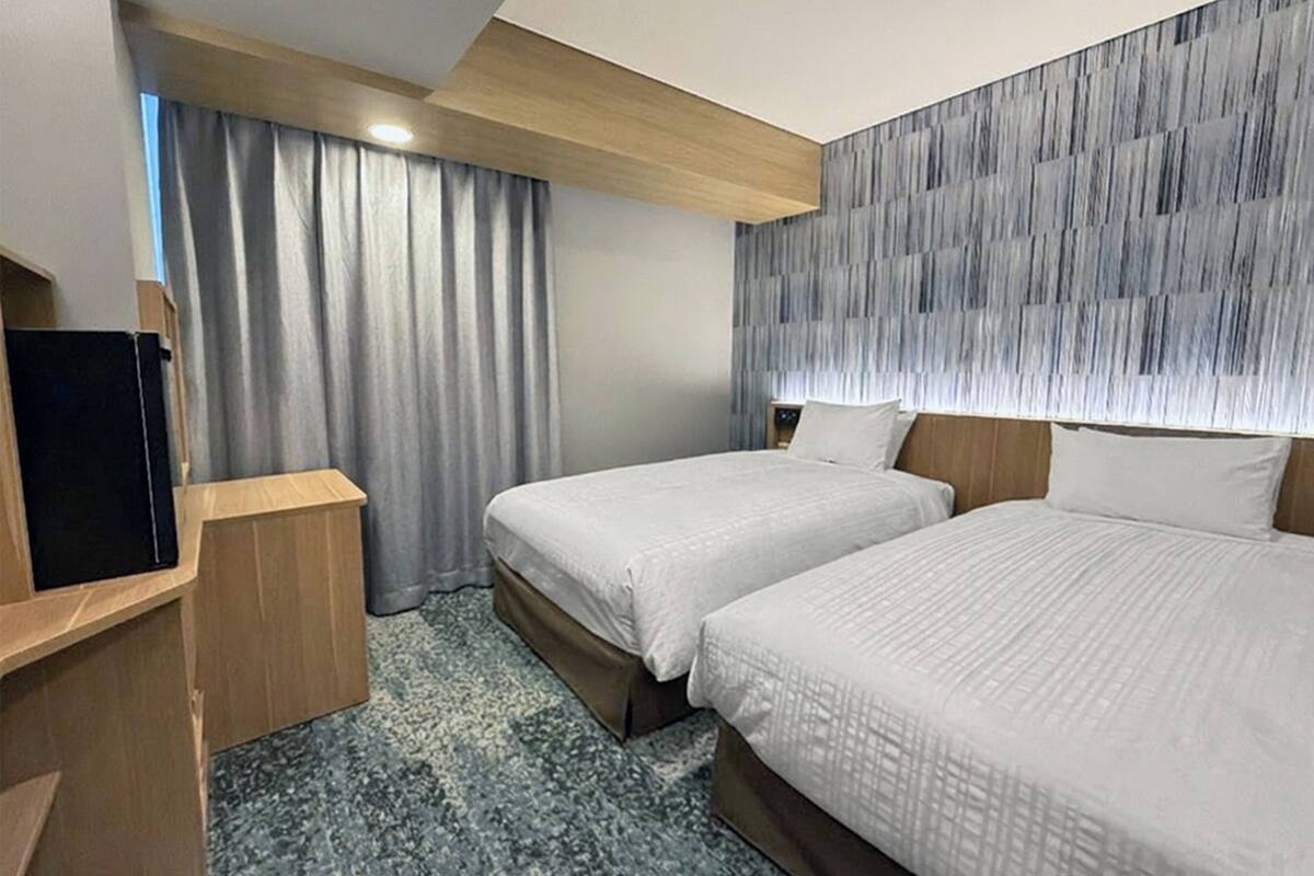 Una habitación de hotel con dos camas, un televisor y un escritorio de madera.