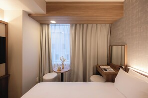 A hotel room with a bed, a small table with a vase, two chairs, a desk with a mirror, and a window with curtains. - Hotel Gracery Sapporo (Sapporo)
