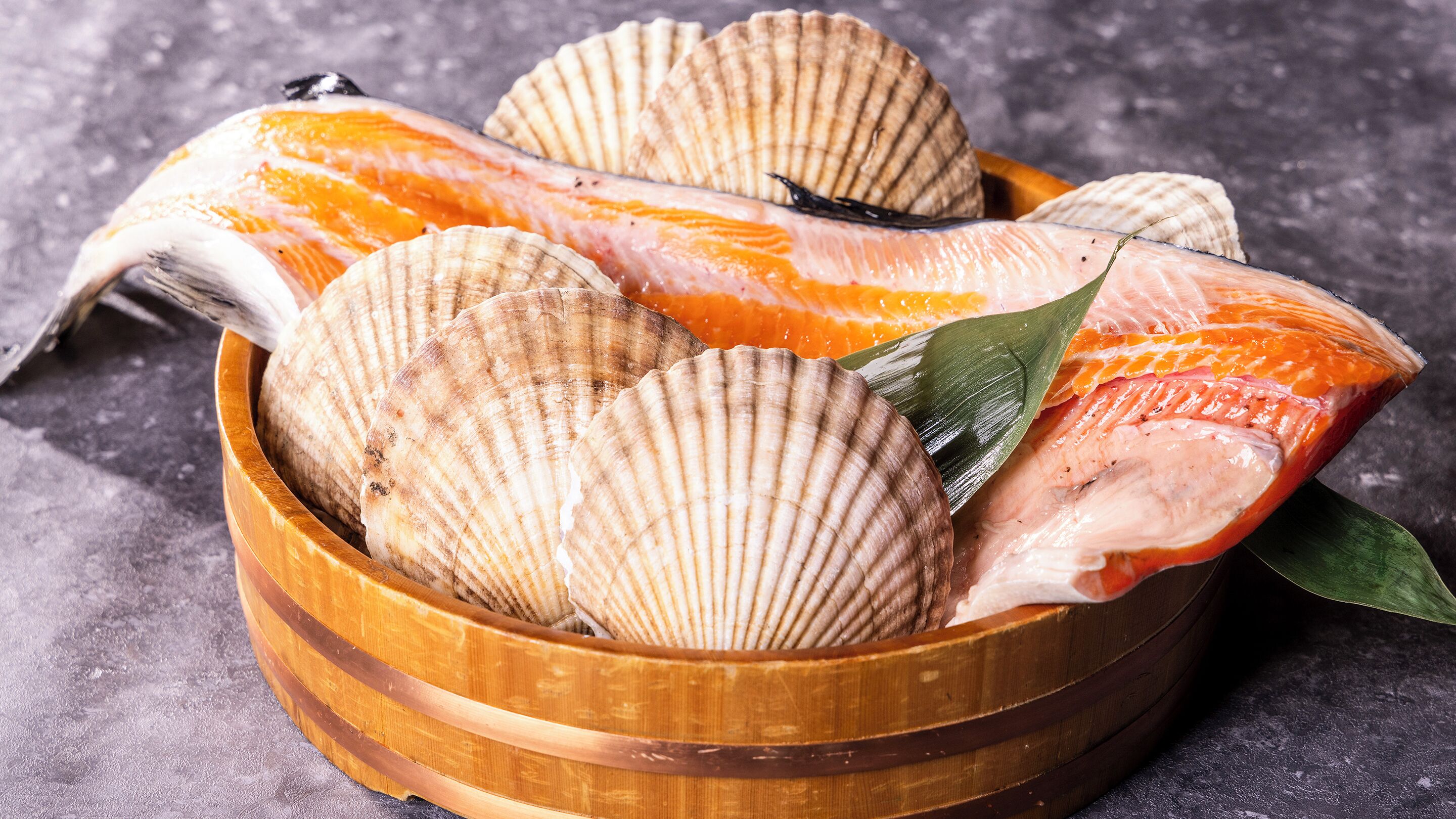 A wooden bowl containing fish and scallops.