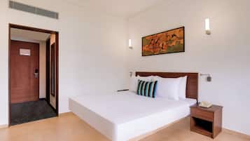 Habitación de hotel con una cama grande, cabecera de madera, mesita de noche con teléfono y un cuadro en la pared.