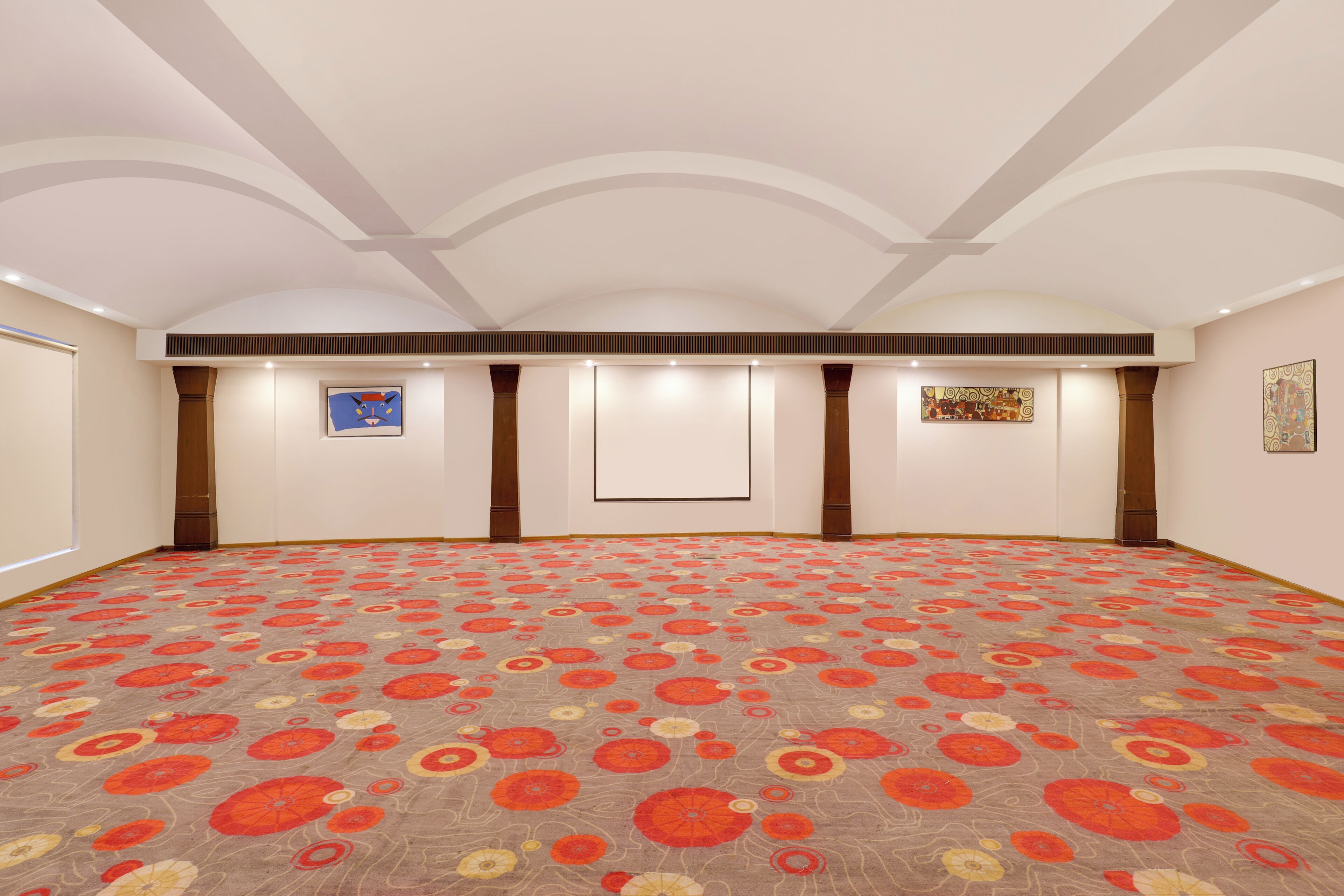 Una habitación amplia con alfombra estampada, iluminación empotrada y obras de arte en las paredes.