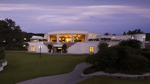 A modern building with a curved facade, large windows, and a well-maintained lawn. - Lemon Tree Hotel, Aurangabad (Chhatrapati Sambhajinagar)