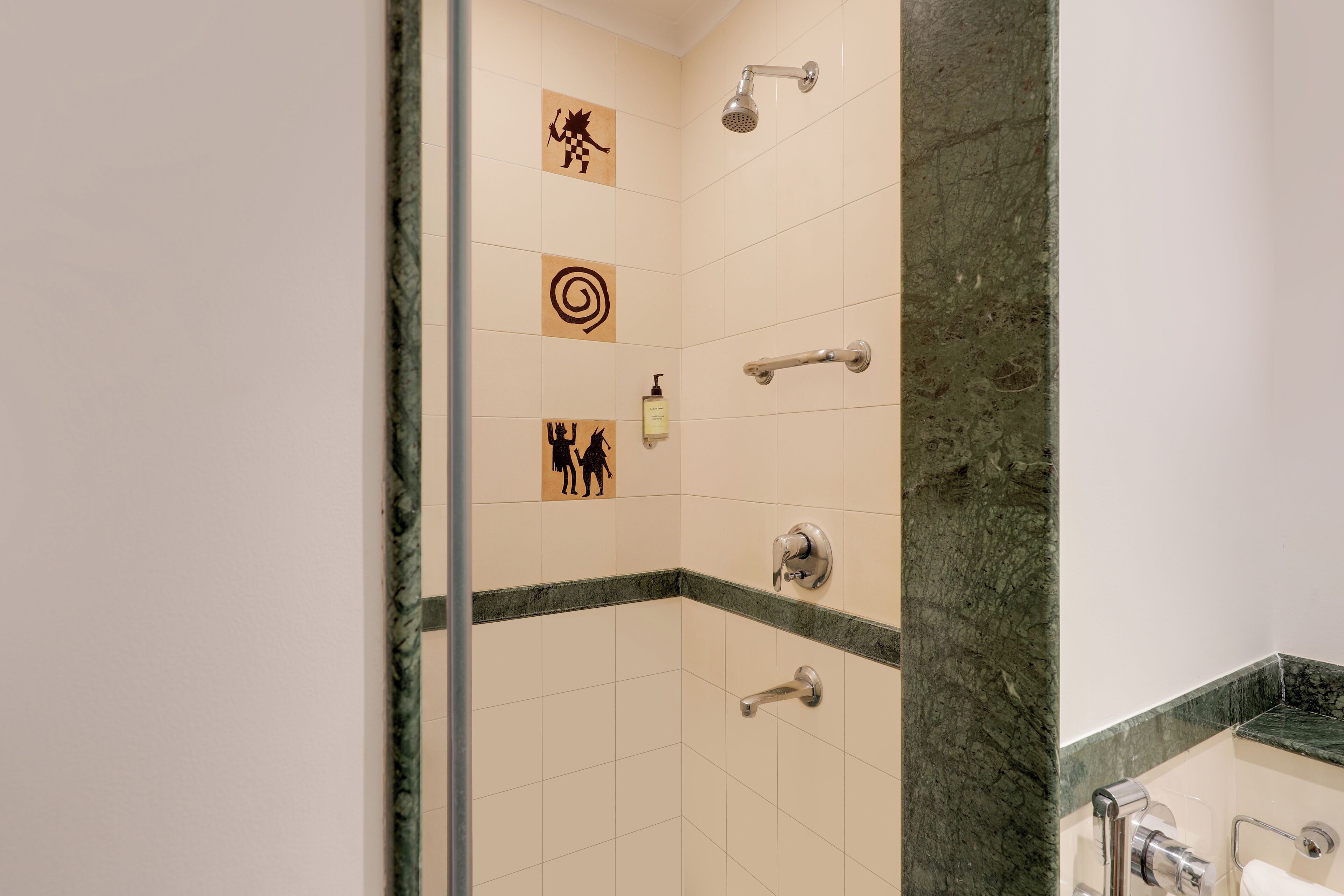 A bathroom with a shower, a hand dryer, and a soap dispenser on the wall.
