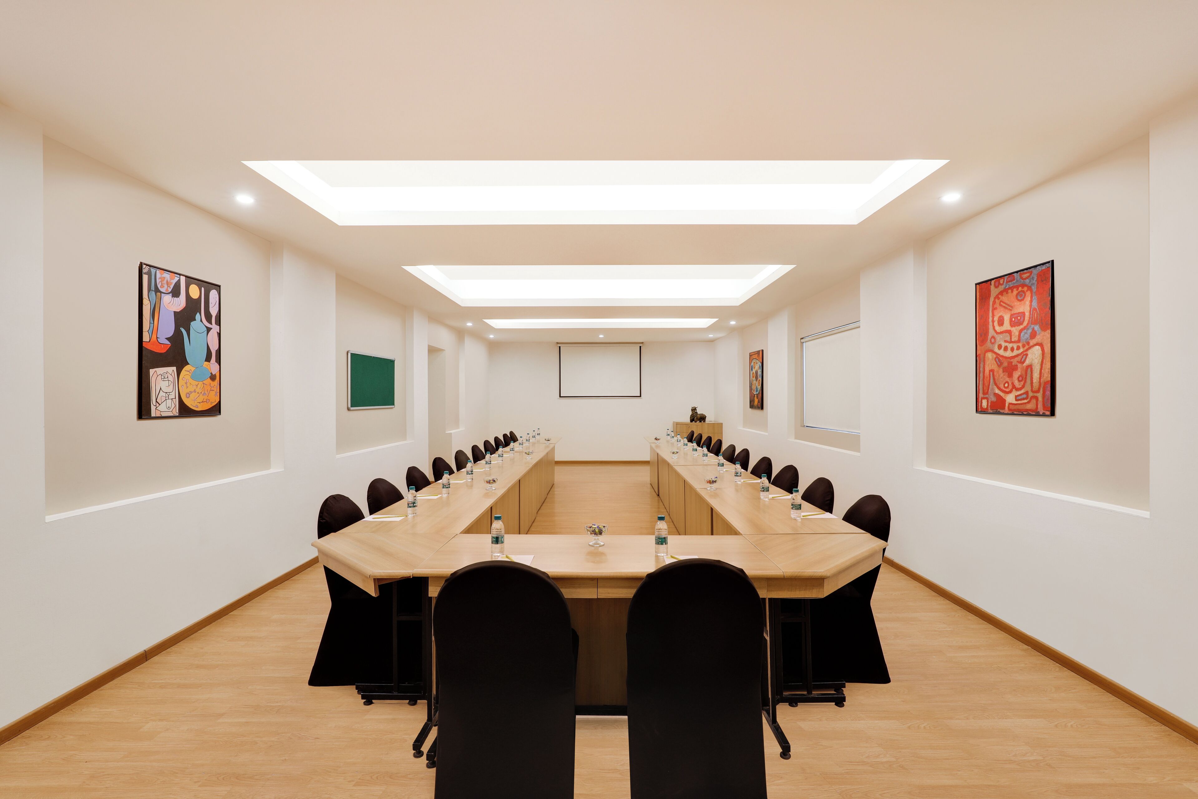 Ein Konferenzraum mit einem langen Tisch, schwarzen Stühlen und Kunstwerken an den Wänden.