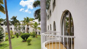 A courtyard with palm trees, a white building with arched windows, and a tiled floor. - Lemon Tree Hotel, Aurangabad (Chhatrapati Sambhajinagar)