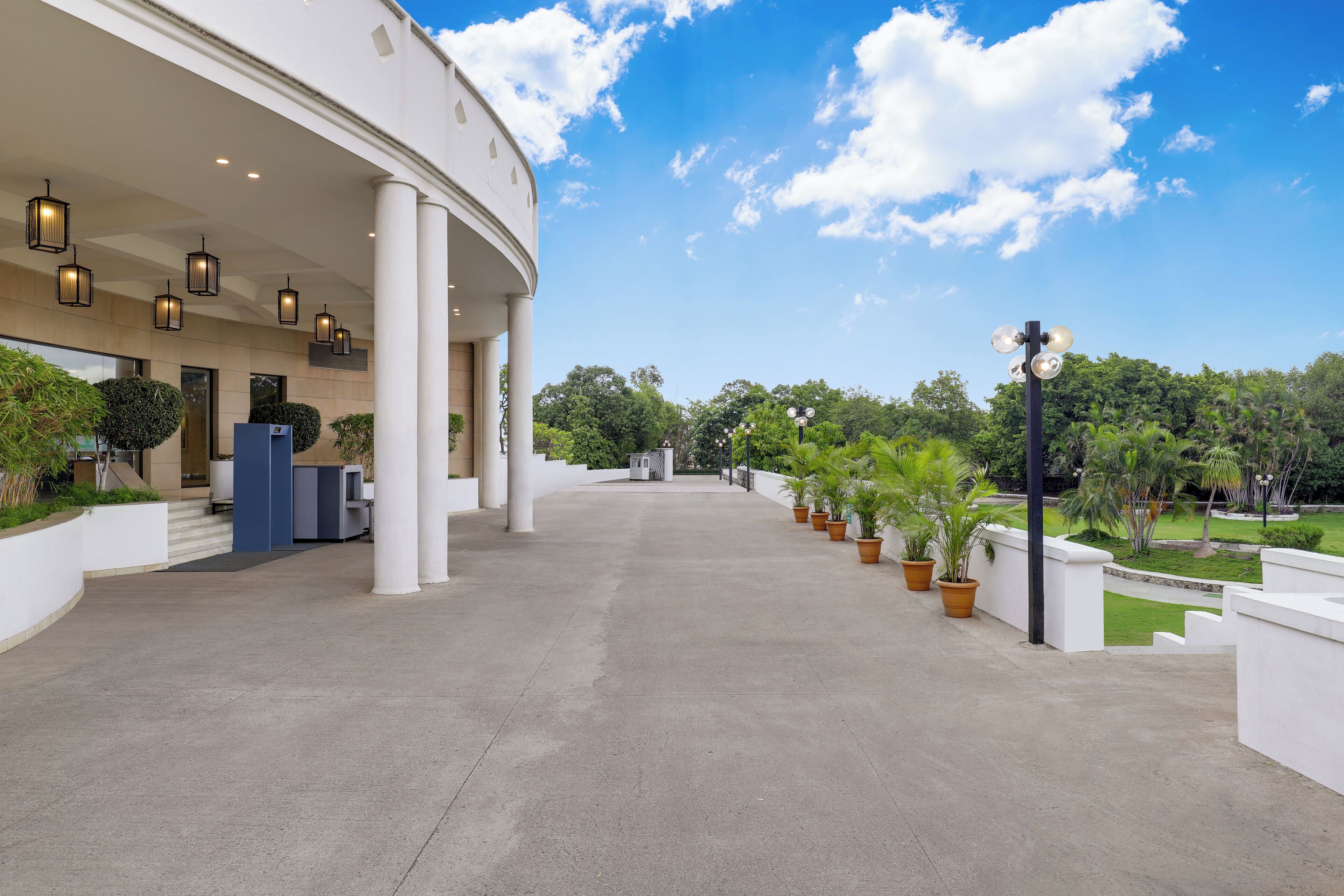A spacious outdoor area with a curved building, potted plants, and a clear sky.