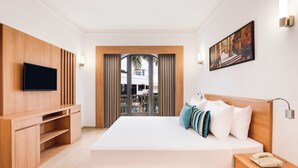 A modern hotel room with a large bed, a TV, a wooden cabinet, a bedside table with a phone, and a painting on the wall. - Lemon Tree Hotel, Aurangabad (Chhatrapati Sambhajinagar)