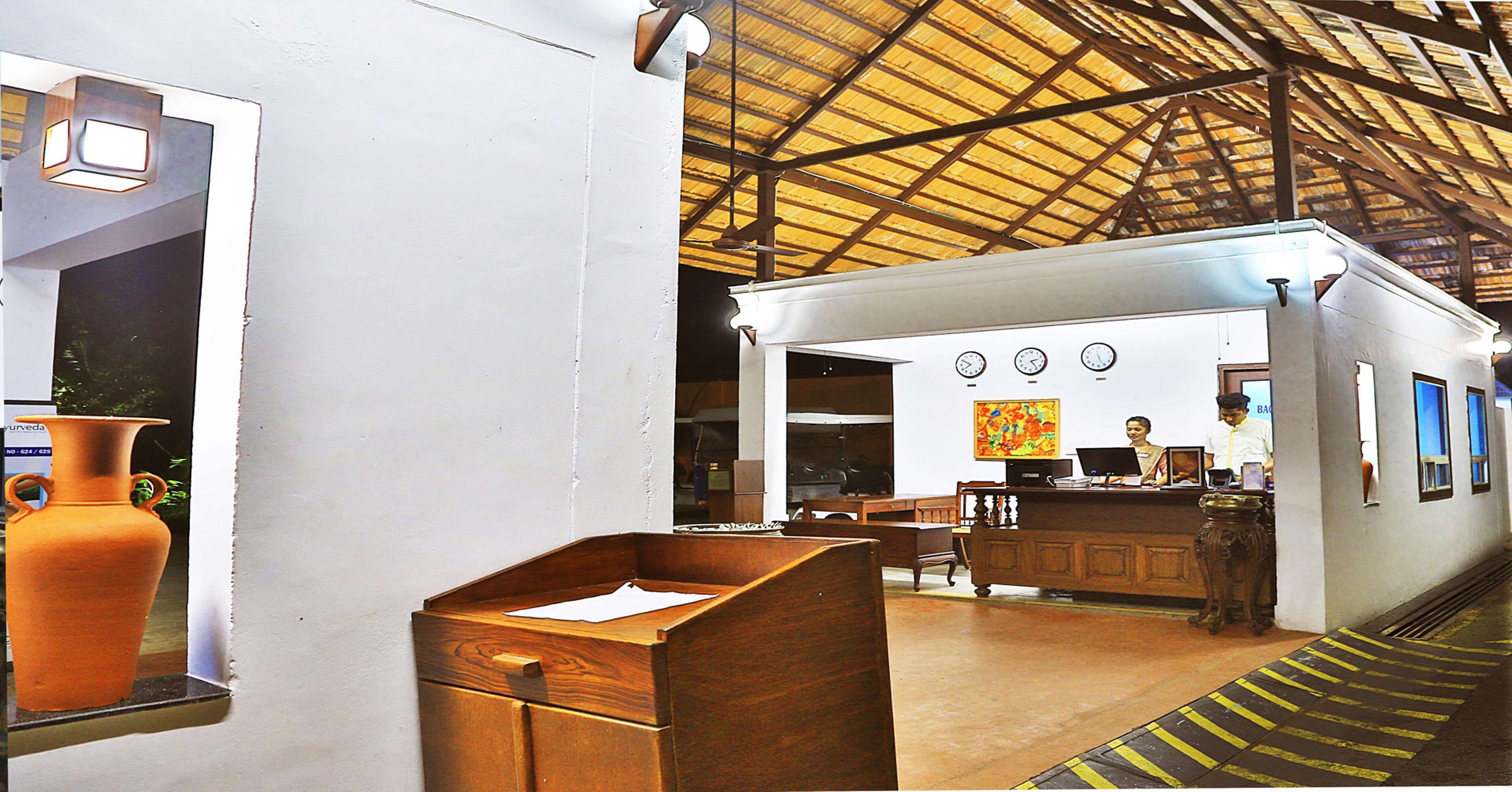 A reception area with a wooden desk, a vase, and a clock on the wall.