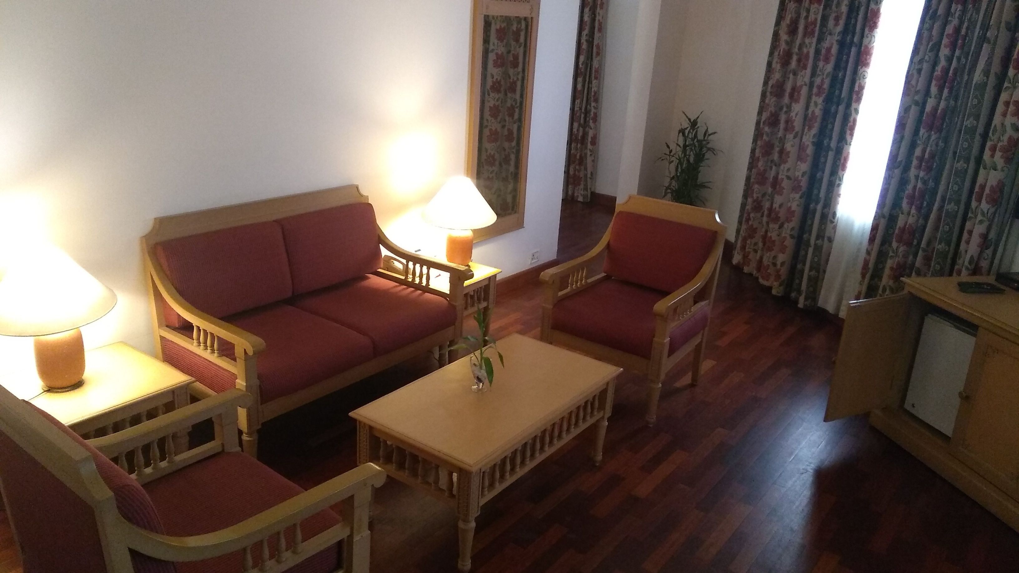 Una sala de estar con sofá, dos sillones, una mesita de centro y una lámpara.