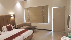 Habitación de hotel con cama, sofá, una mesita y televisor.