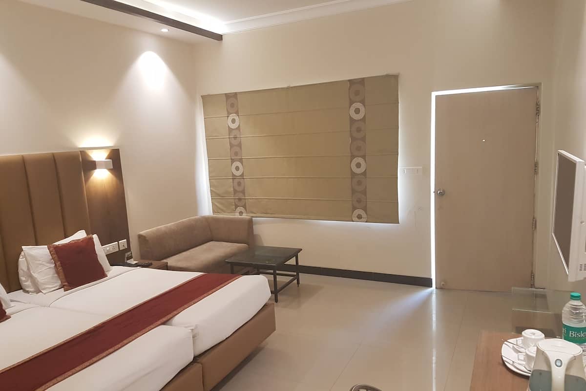 A hotel room with a bed, sofa, small table, and a television.
