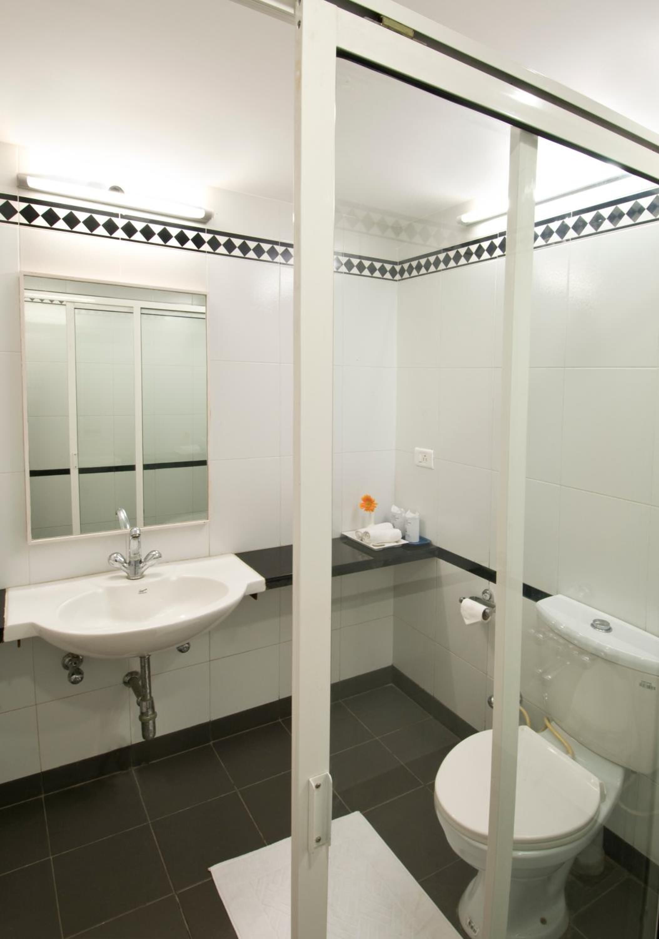 Un baño con lavamanos, espejo y retrete blancos.
