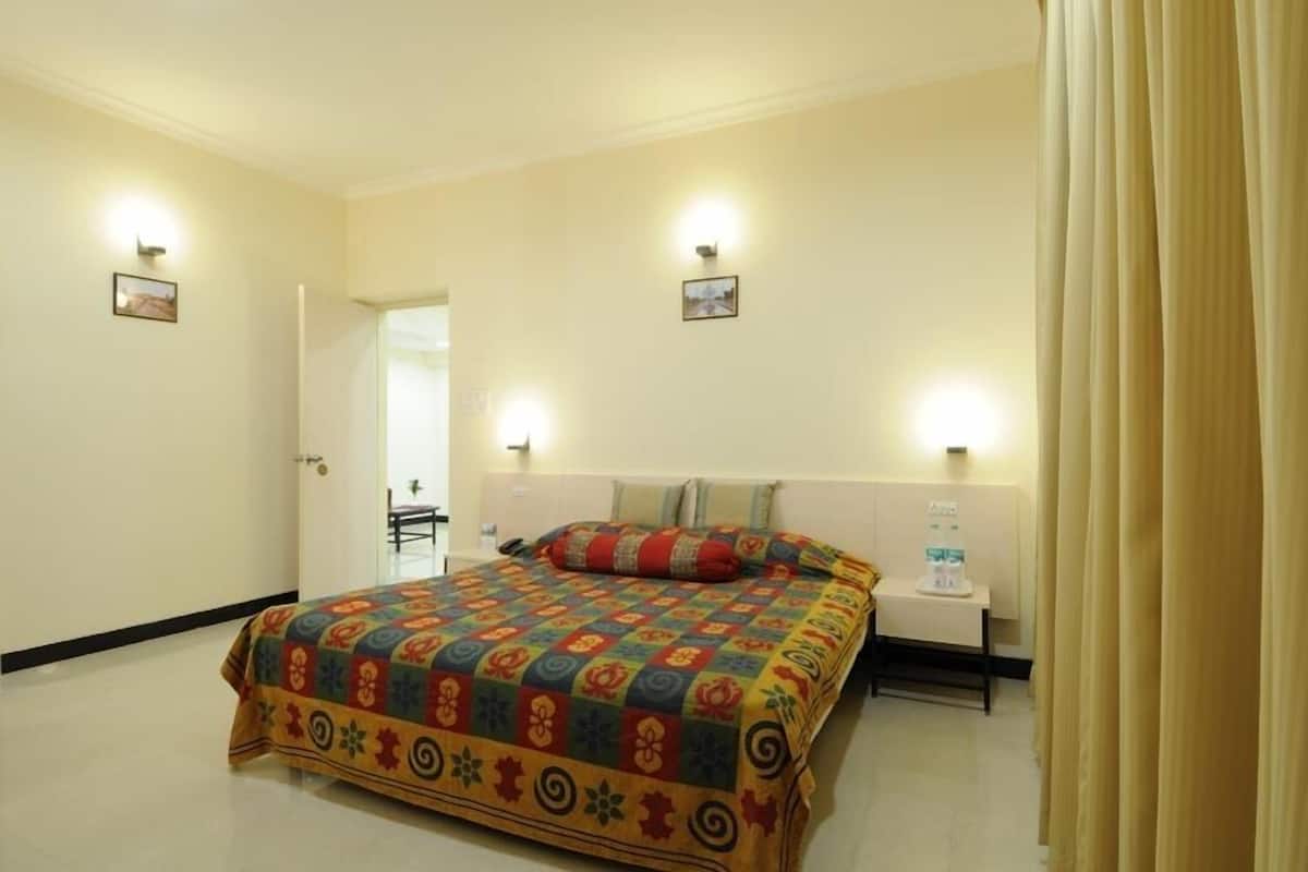 A hotel room with a bed, bedside table, and two wall-mounted lights.