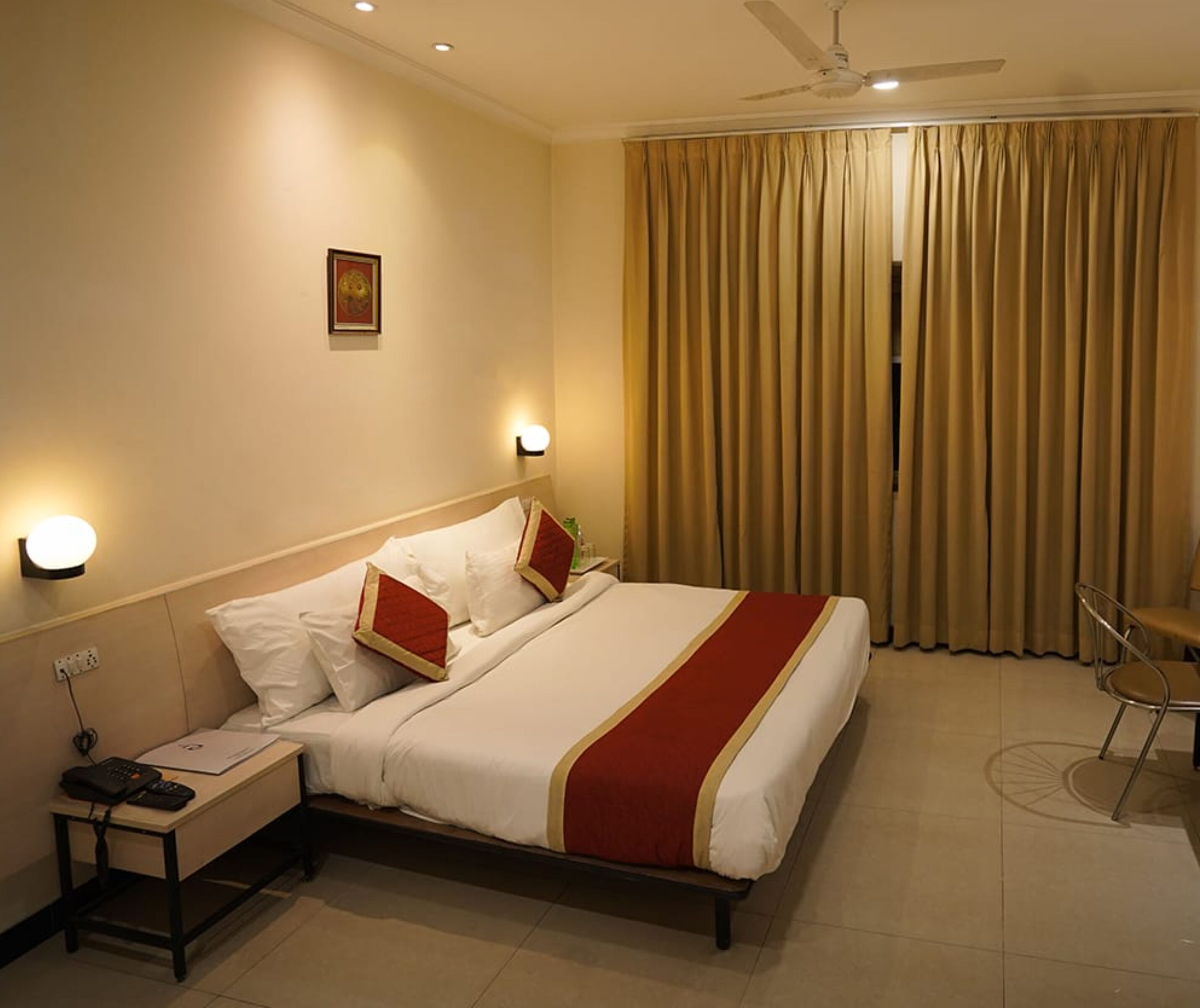 Ein Hotelzimmer mit Bett, Nachttisch, Lampe und einem Sessel.