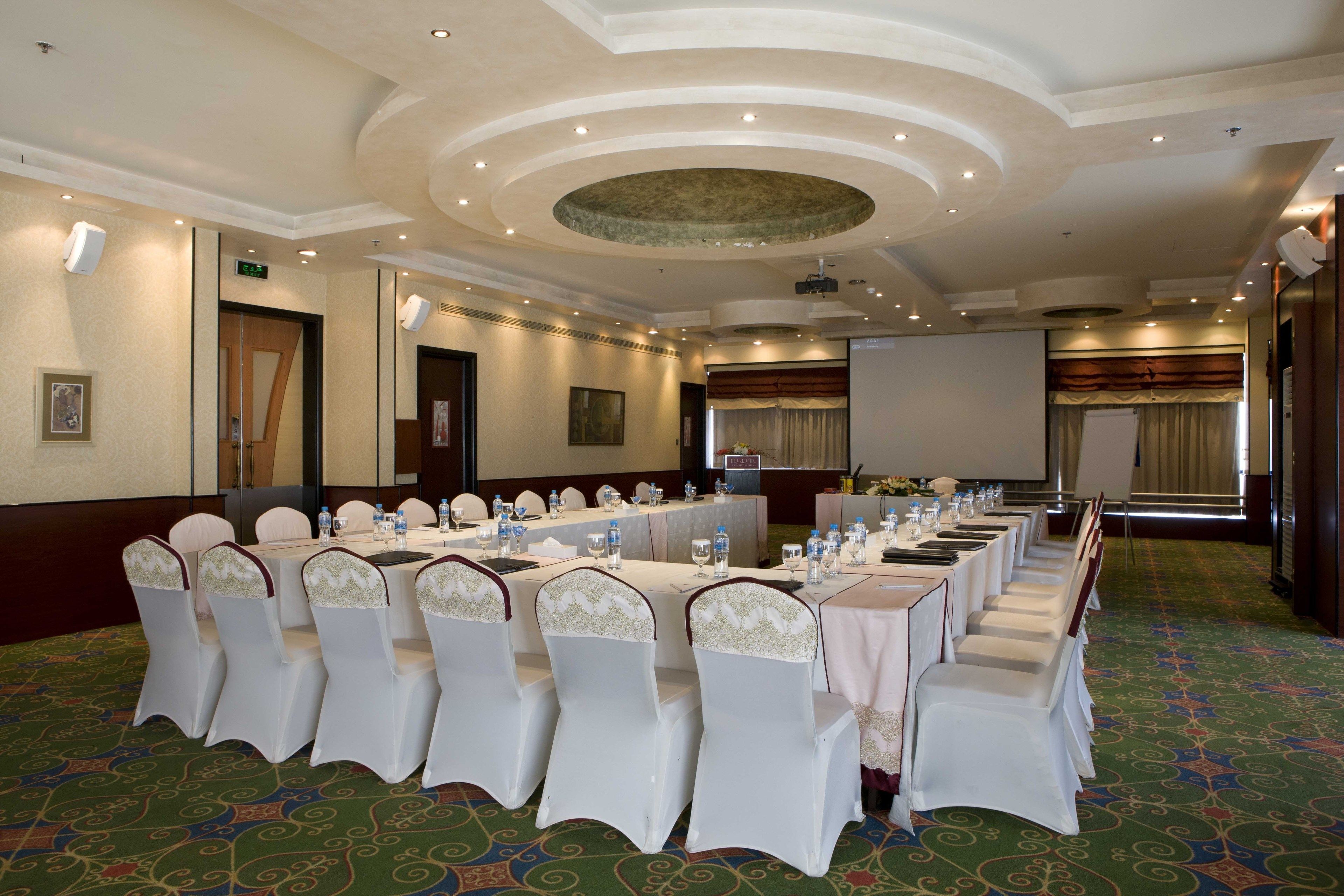 A conference room with a long table, white chairs, and a carpeted floor.