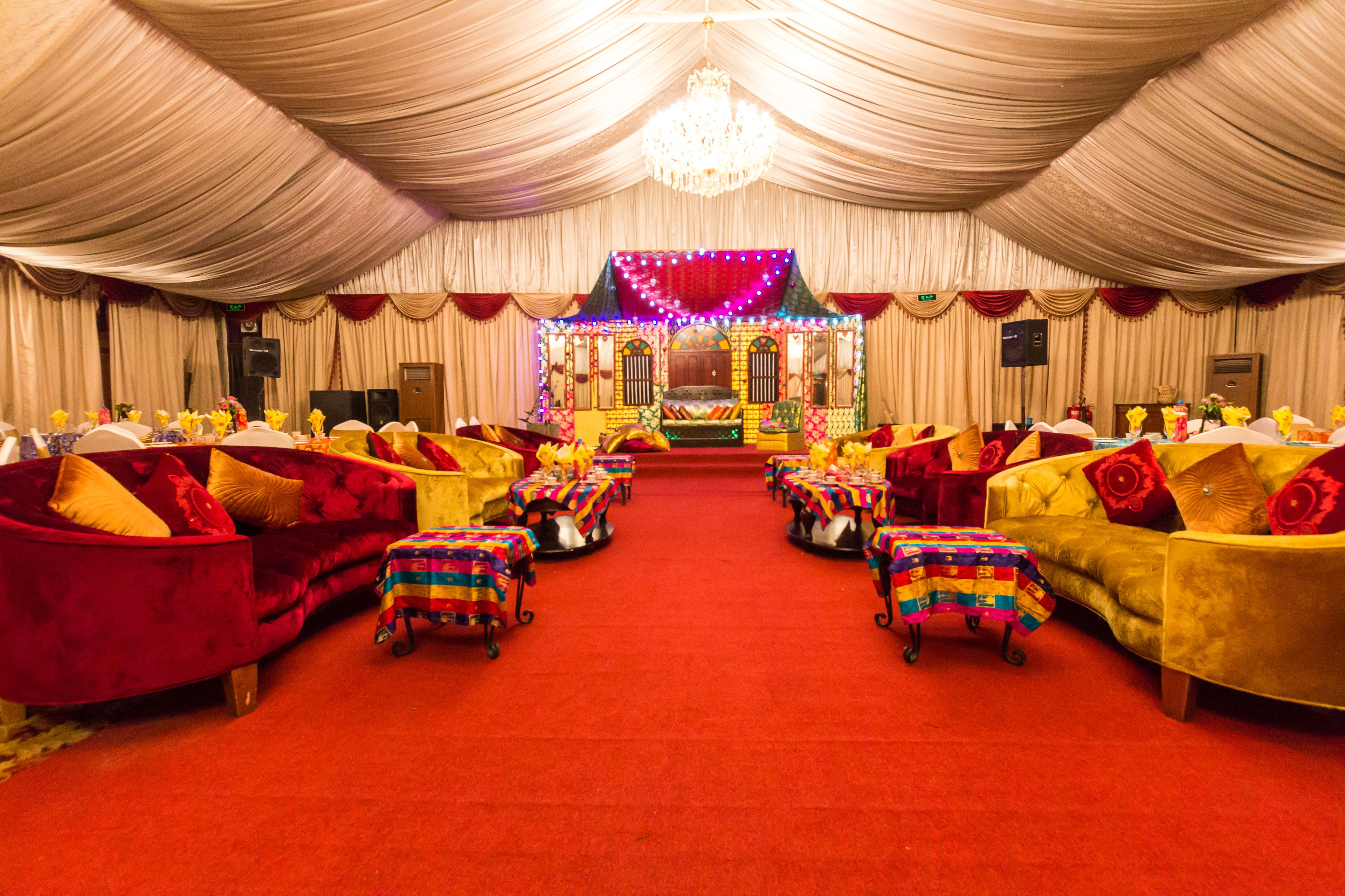 A banquet hall with tiered seating, red carpet, and chandeliers.