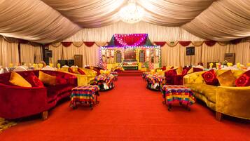 A banquet hall with tiered seating, red carpet, and chandeliers.