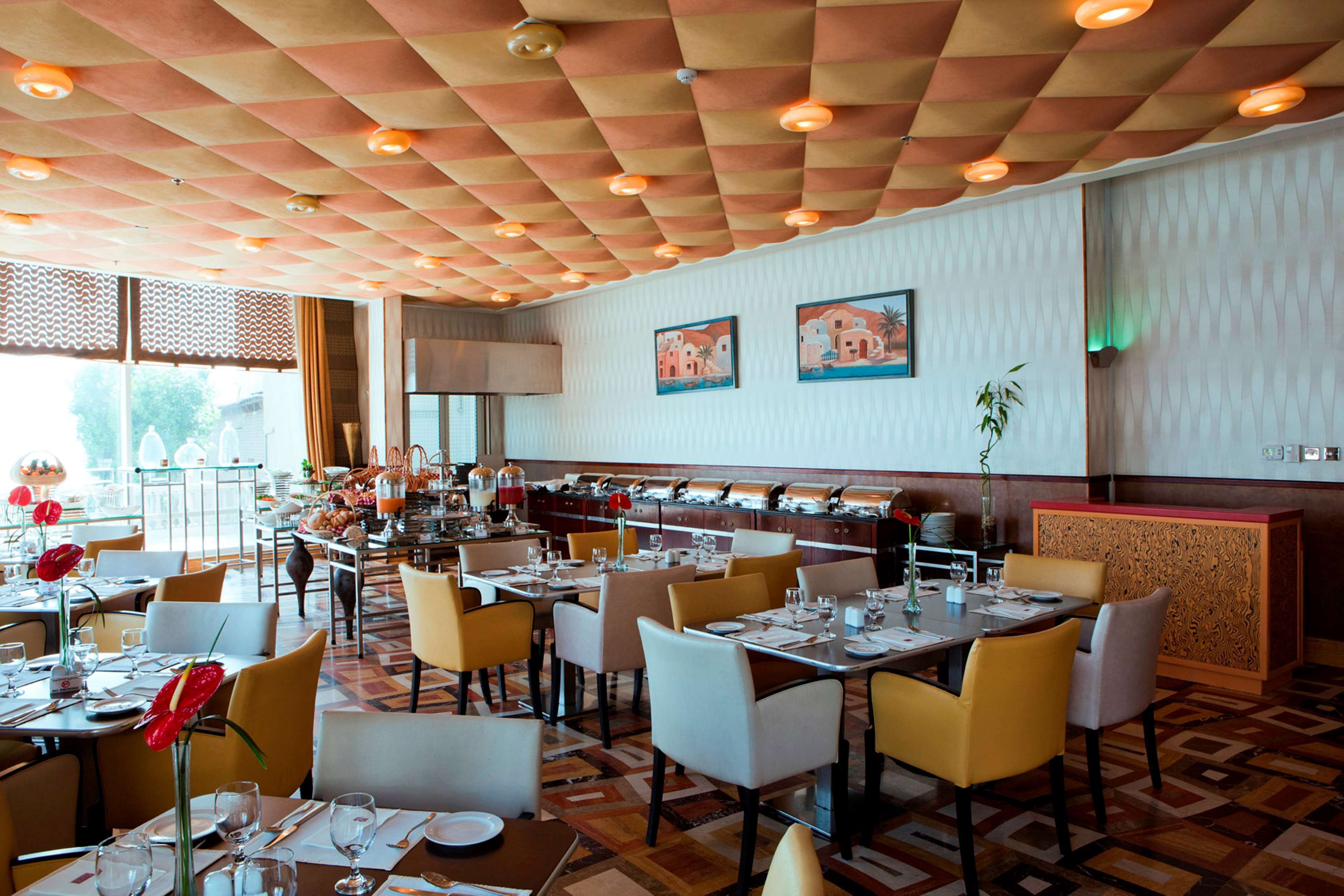 A restaurant with a checkered ceiling, multiple dining tables, and chairs.