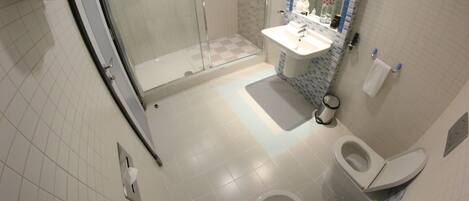A bathroom with a glass shower enclosure, a sink with a mirror, and a toilet.