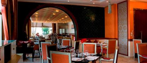 A restaurant with tables and chairs, a chandelier, and a large archway.