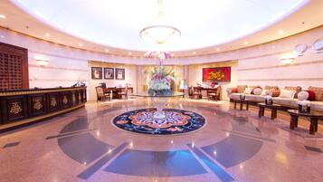 A spacious lobby with a central decorative fountain, seating areas, and a reception desk.