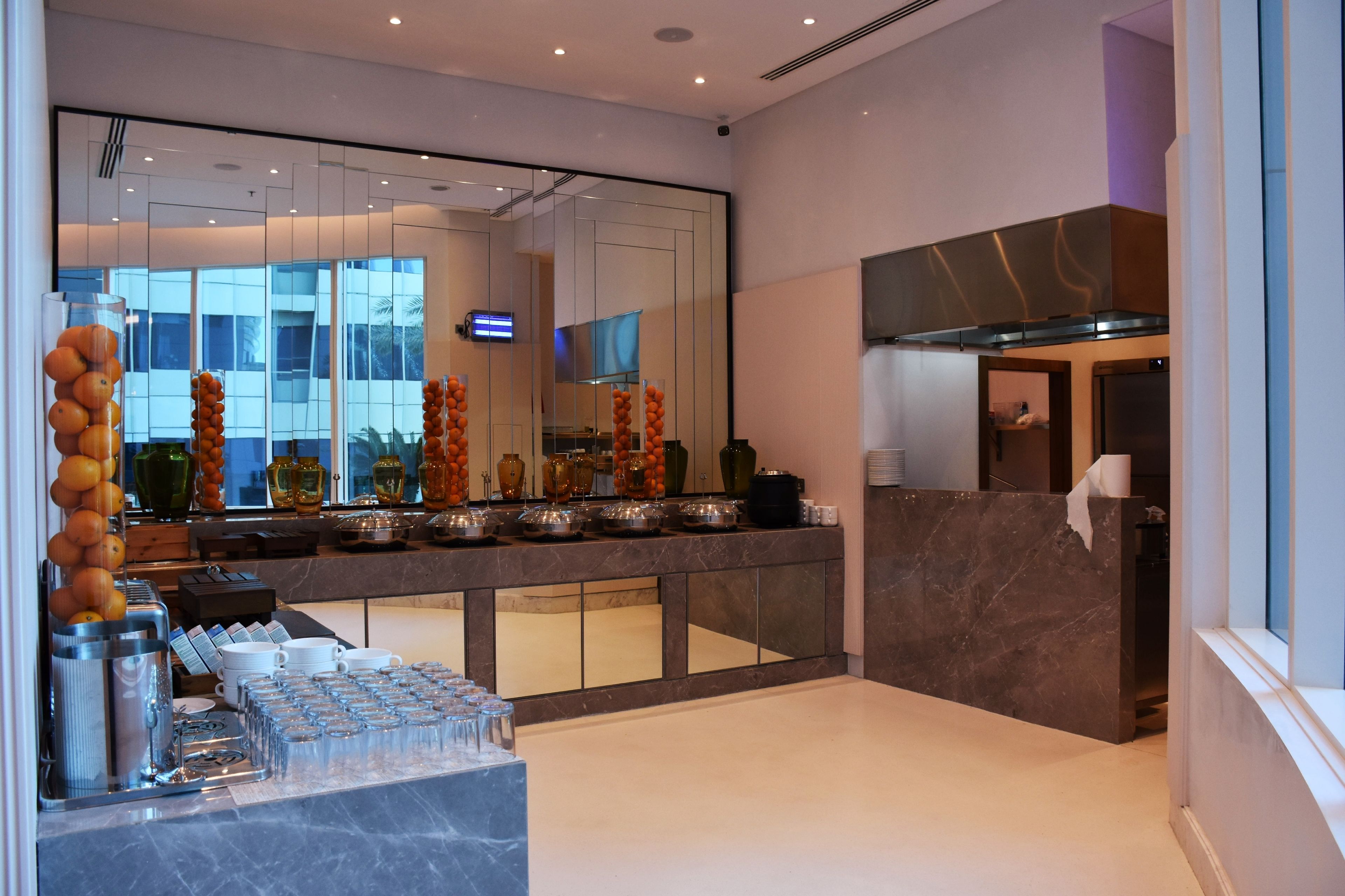 A modern kitchen with a marble countertop, glassware, and a view of the building outside.