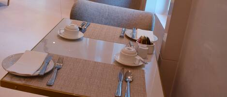 A modern dining area with tables set for two, featuring a neutral color palette and contemporary furniture.