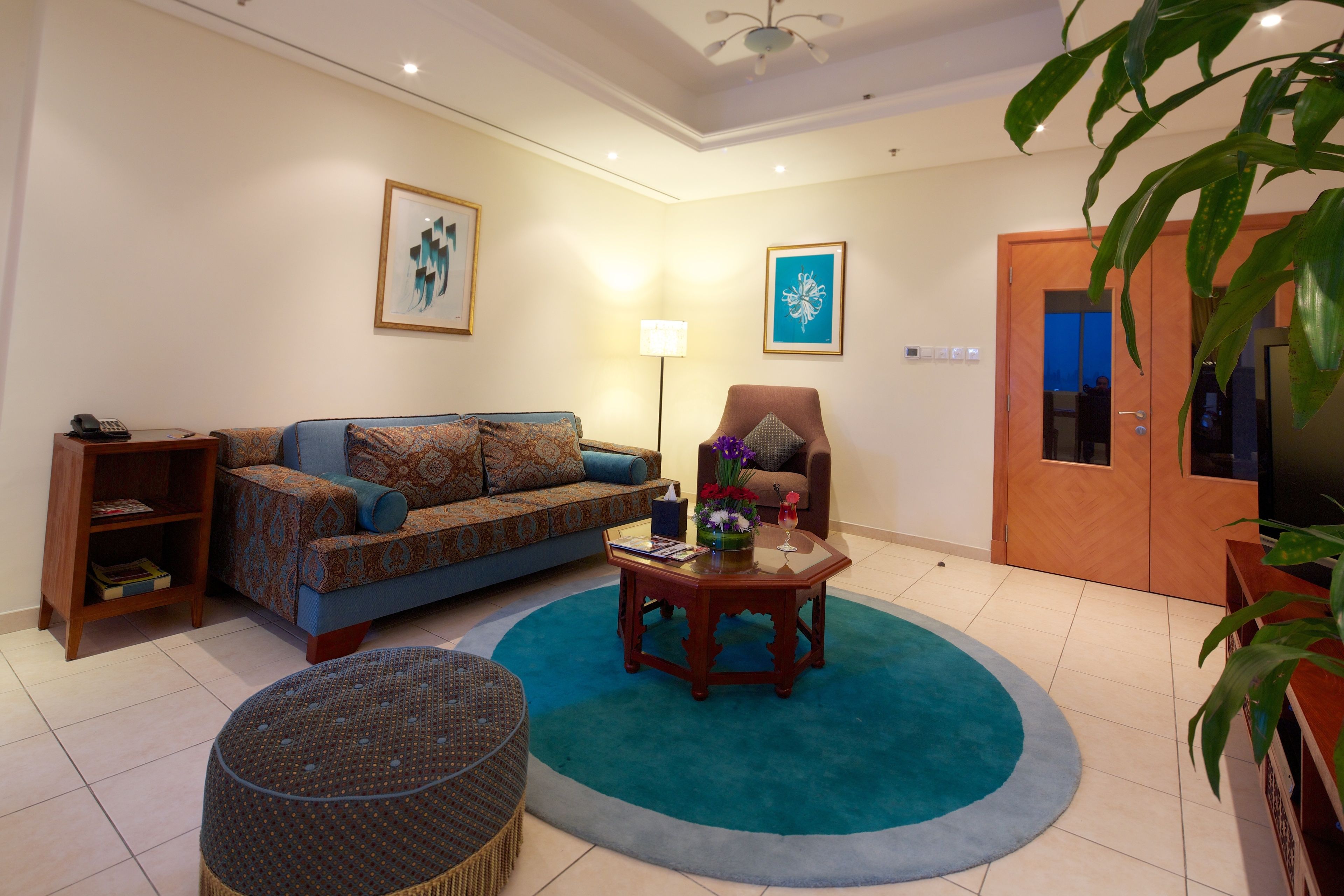 A living room with a sofa, armchair, coffee table, and a large potted plant.