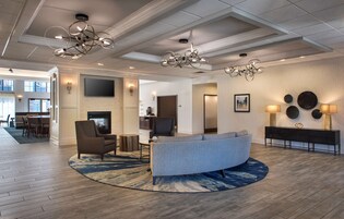 A spacious living area with a curved sofa, a fireplace, and a modern chandelier.