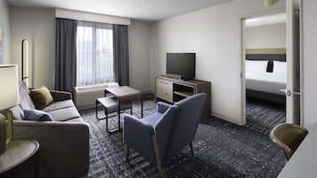Habitación de hotel con sofá, escritorio, silla, televisor y cama.