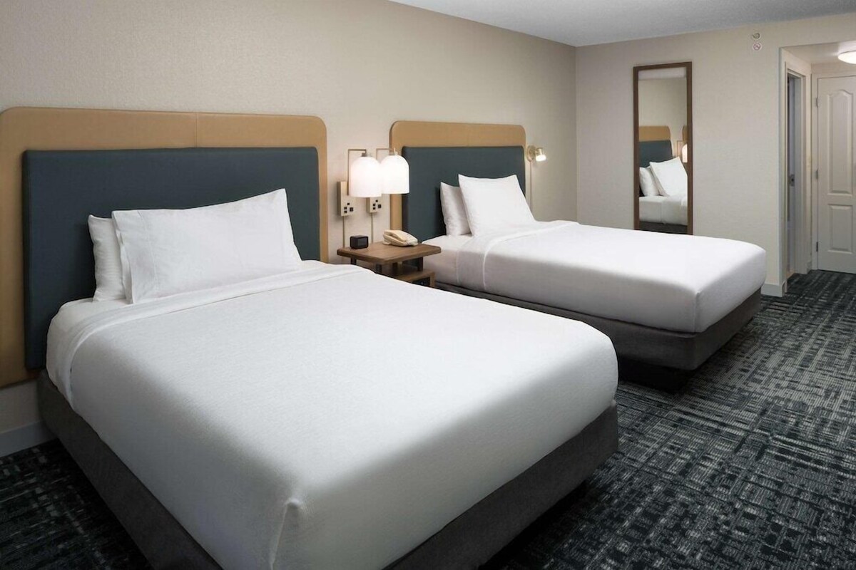 Een hotelkamer met twee bedden, een nachtkastje met een telefoon en een spiegel.