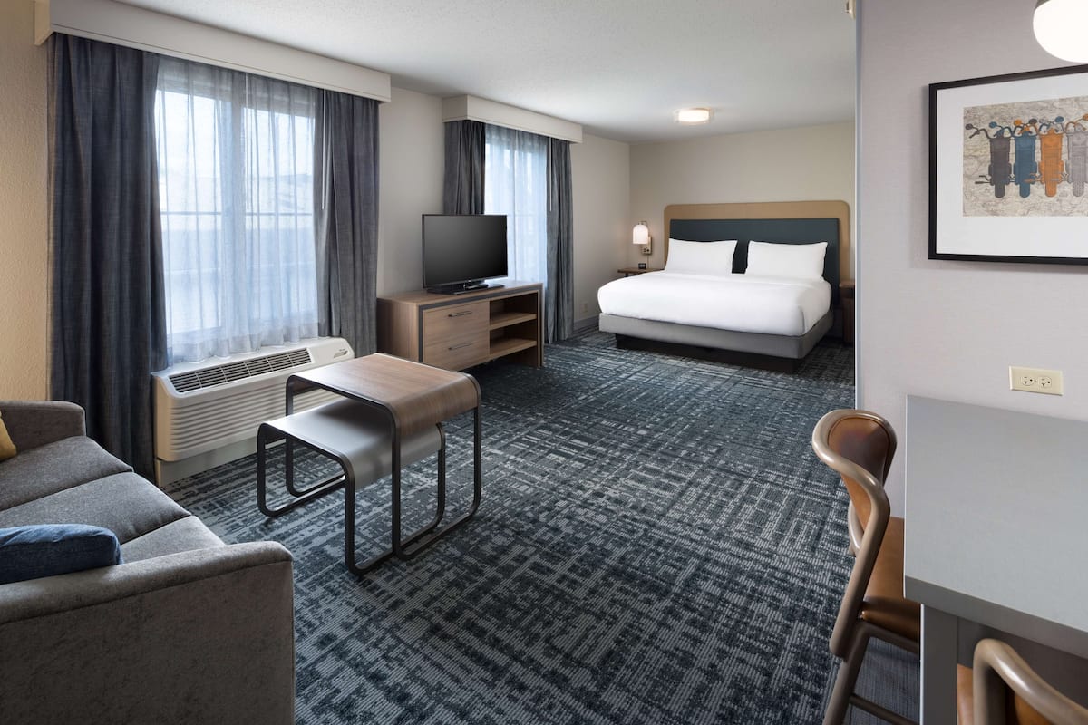 A hotel room with a bed, a TV, a desk, and a chair.