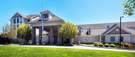 A multi-story hotel with a prominent entrance, stone pillars, and a well-maintained lawn.