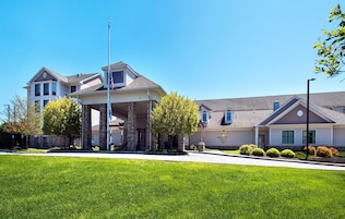 A multi-story hotel with a prominent entrance, stone pillars, and a well-maintained lawn.