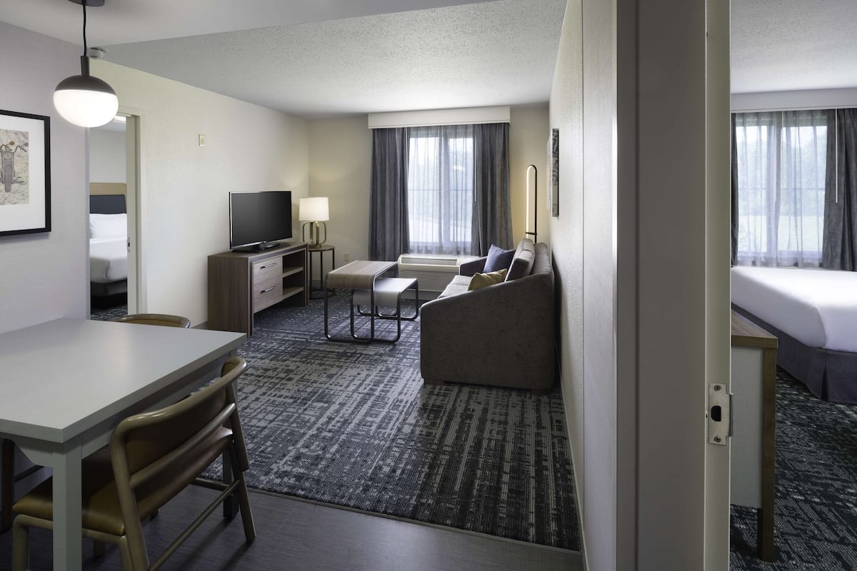 A hotel room with a bed, a sofa, a TV, a desk, and a chair.