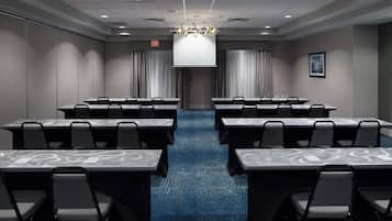 A conference room with a large screen, multiple tables, and chairs.