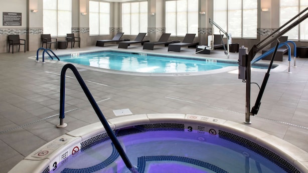 Ein Hotel-Innenpool mit Liegestühlen, einer Whirlpool und einem Warnschild.