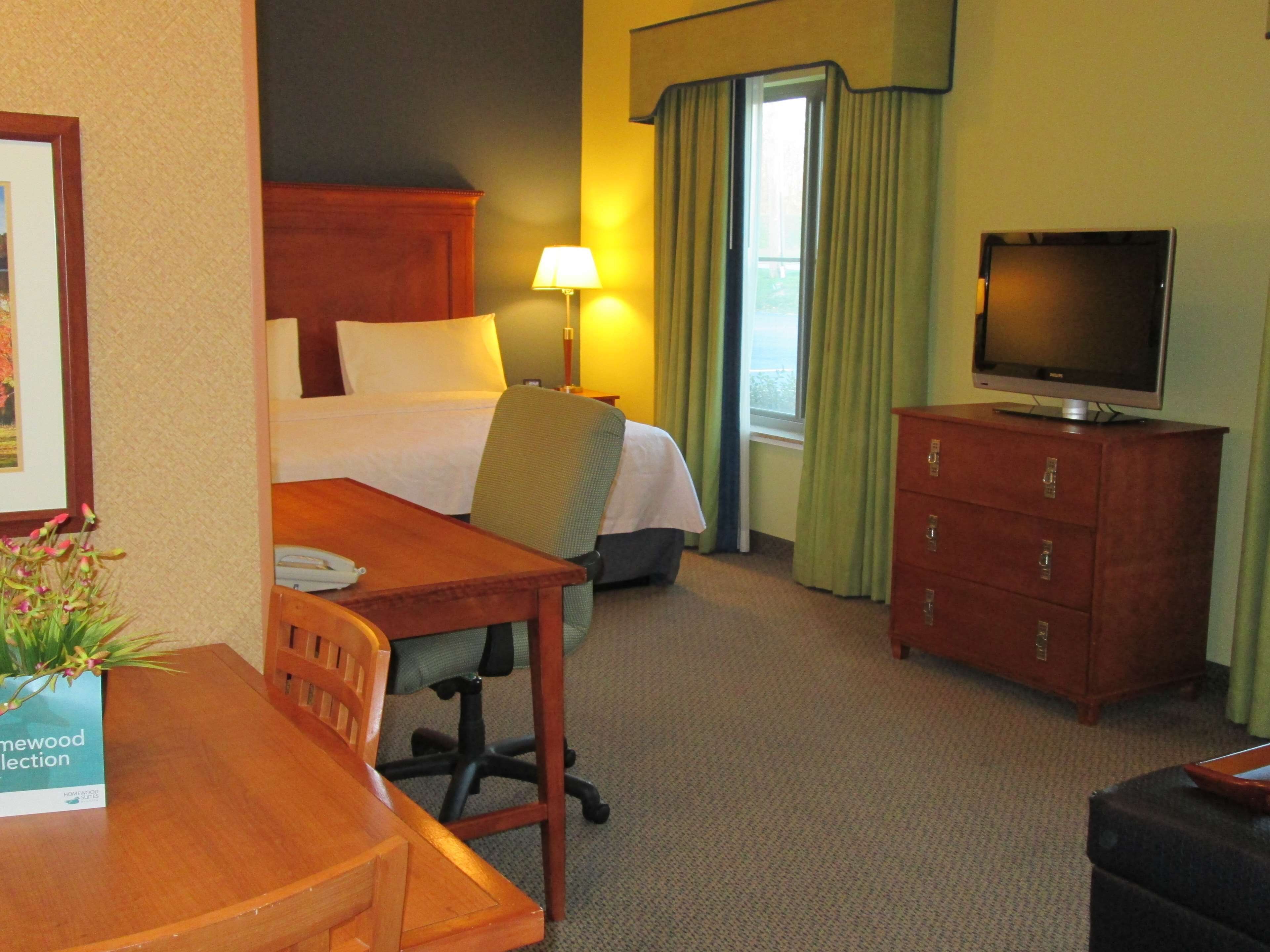 Una habitación de hotel con una cama, un escritorio, una silla, un televisor y un aparador.