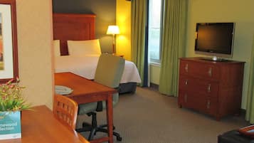 Una habitación de hotel con una cama, un escritorio, una silla, un televisor y un aparador.
