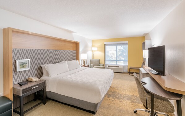 Habitación de hotel con cama, escritorio, silla, televisor y ventana con vistas.