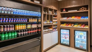 Una sección bien organizada de bebidas y aperitivos, con diversas marcas y tipos de refrescos y jugos, además de una selección de bocadillos y alimentos envasados.