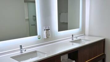 A modern bathroom with two sinks, a large mirror, and a wooden vanity with a towel rack.