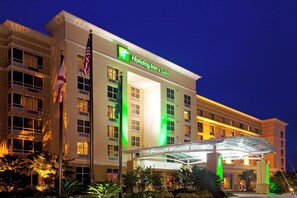 A Holiday Inn & Suites hotel with a clear entrance, multiple floors, and a flagpole with the American flag. - Holiday Inn Hotel & Suites Orange Park by IHG (Orange Park)