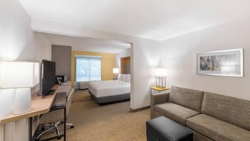 A hotel room with a bed, a desk with a computer, a couch, and a TV.