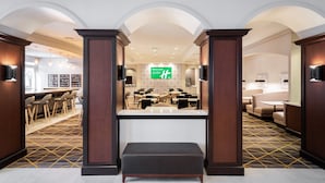A hotel lobby with a reception desk, seating area, and a large green sign.