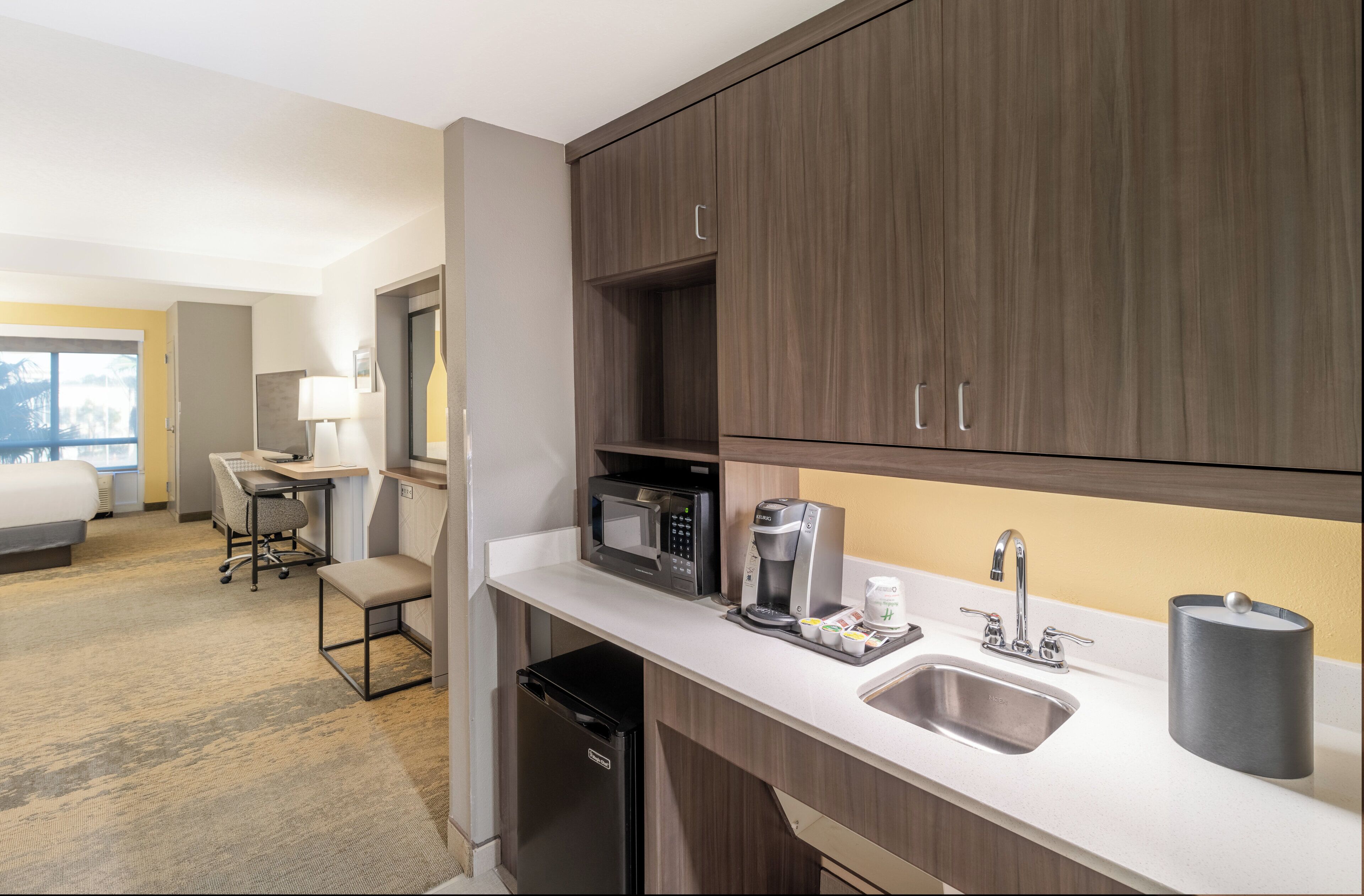 Eine Hotelküche mit Mikrowelle, Kaffeemaschine und Spüle.