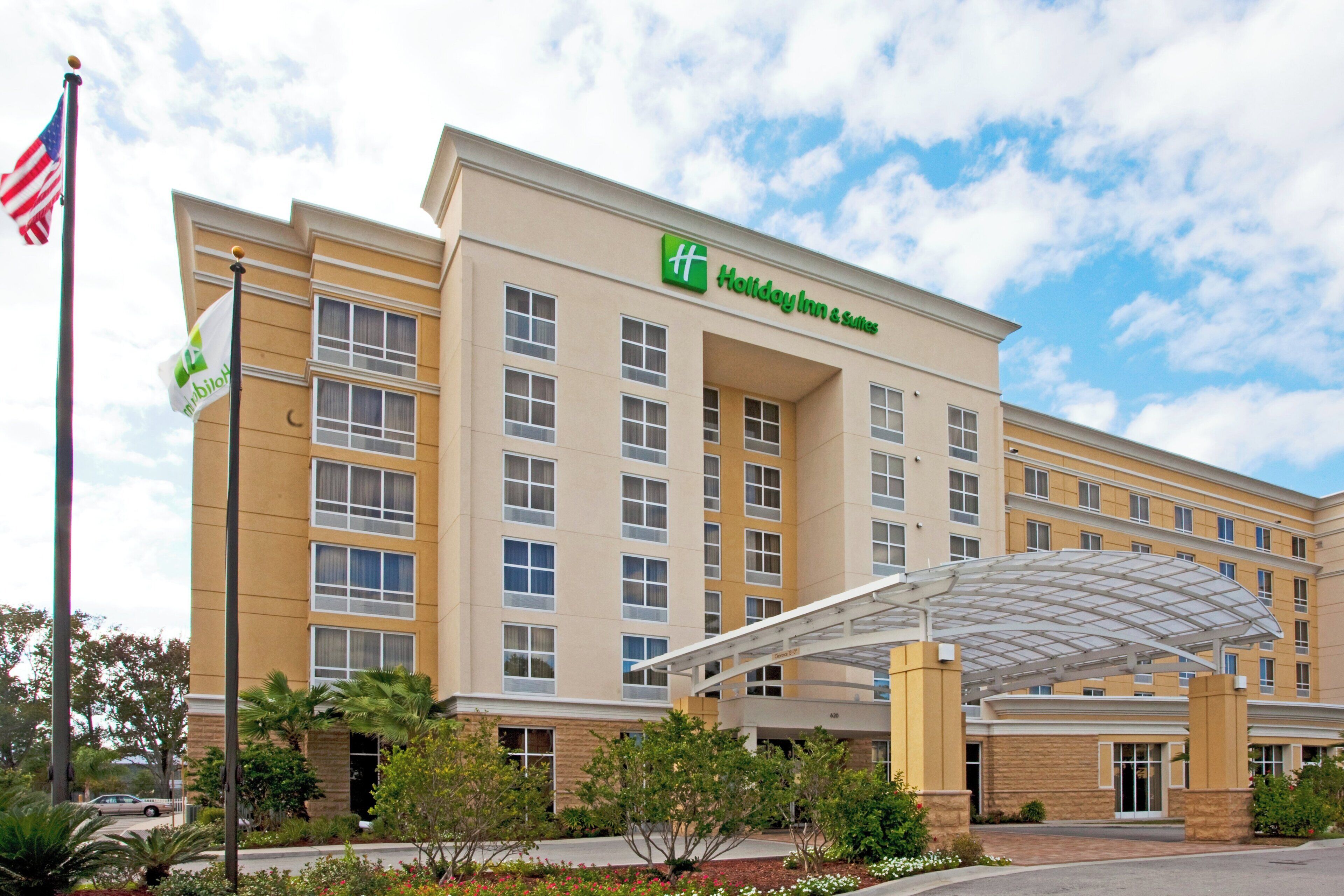 A Holiday Inn & Suites hotel with a covered entrance and a flagpole.