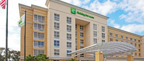 A Holiday Inn & Suites hotel with a covered entrance and a flagpole.